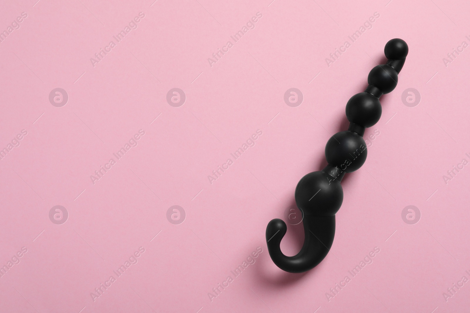 Photo of Black anal ball beads on pink background, top view with space for text. Sex toy