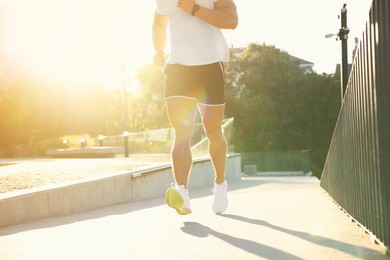 Man running outdoors on sunny day, closeup. Space for text