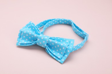 Photo of Stylish light blue bow tie with polka dot pattern on beige background