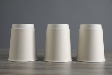 Photo of Shell game. Three paper cups on wooden table