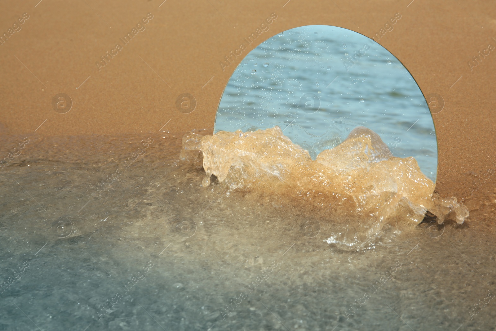 Photo of Round mirror reflecting sea on sandy beach