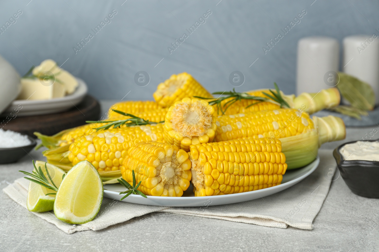 Photo of Tasty boiled corn and ingredients on grey table