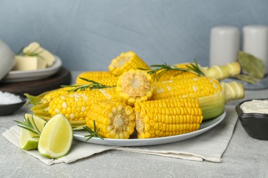 Photo of Tasty boiled corn and ingredients on grey table