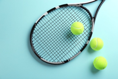 Photo of Tennis racket and balls on light blue background, flat lay. Sports equipment