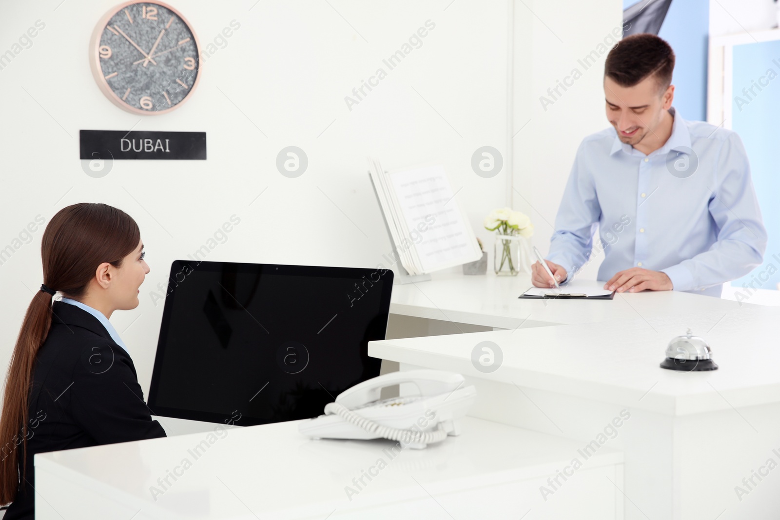 Photo of Young man filling form at reception desk in hotel