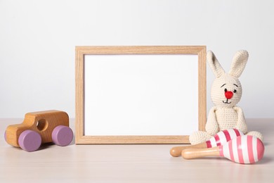 Photo of Empty square frame and different toys on white table
