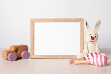 Empty square frame and different toys on white table