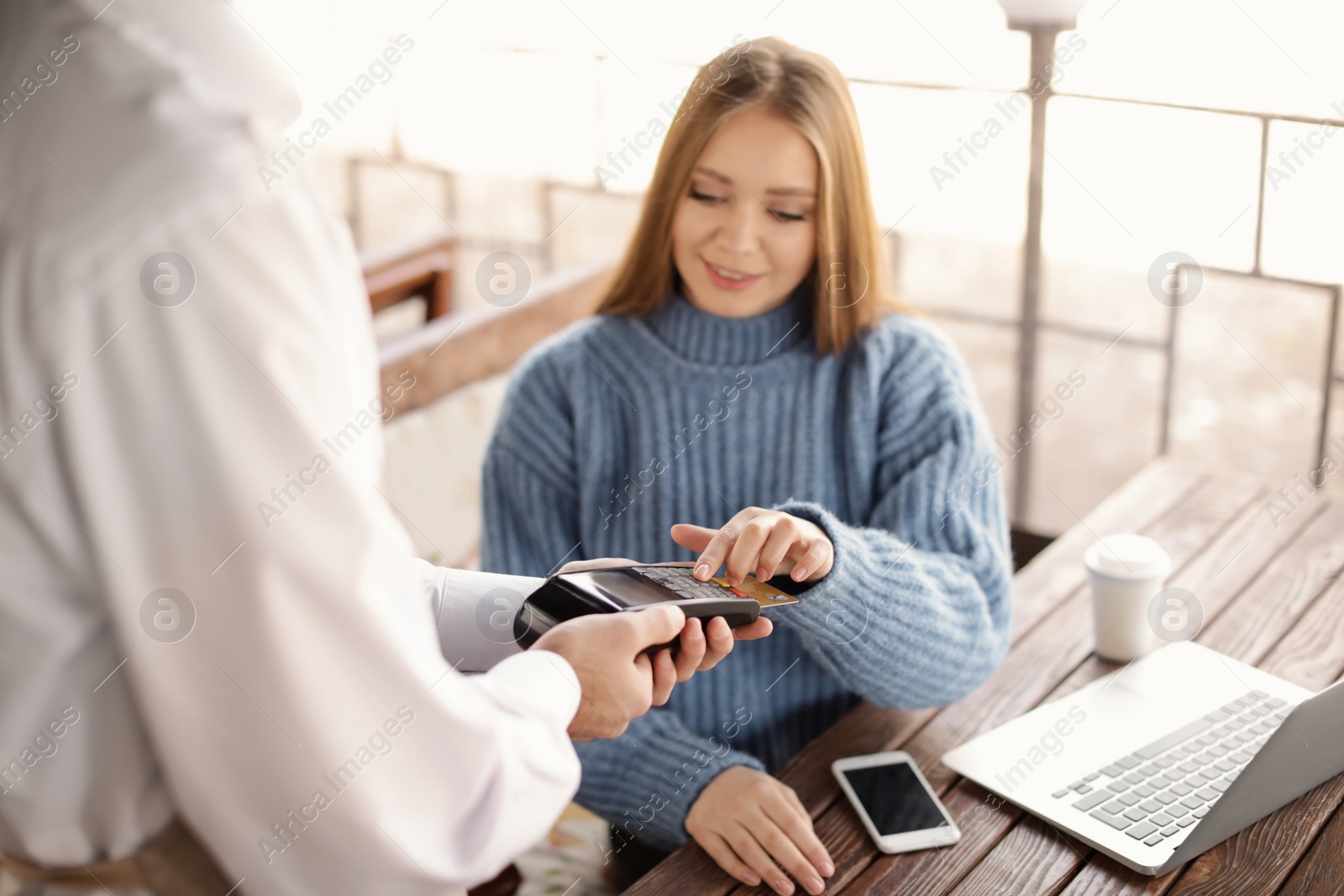 Photo of Woman with credit card using payment terminal at restaurant