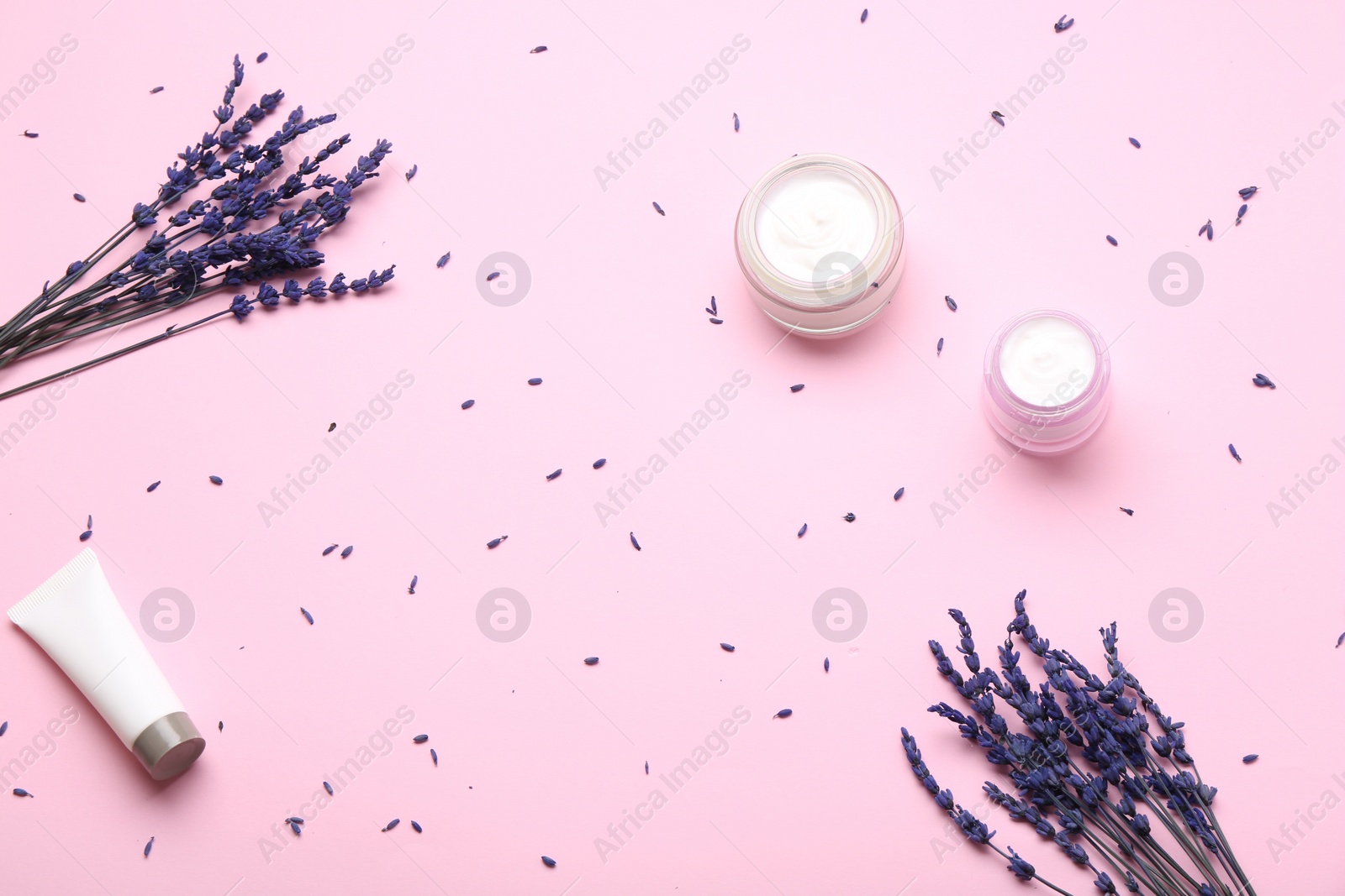 Photo of Jars and tube of cream, lavender flowers on pink background, flat lay