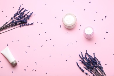 Jars and tube of cream, lavender flowers on pink background, flat lay