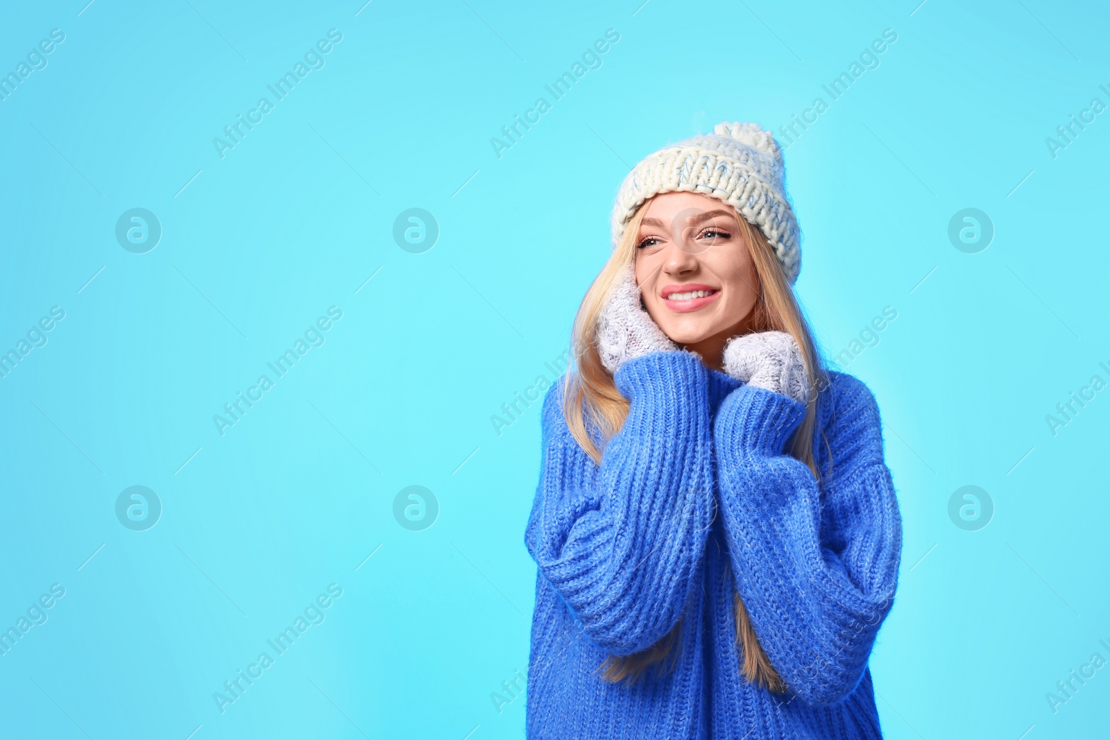 Photo of Portrait of emotional young woman in stylish hat, sweater and mittens on color background, space for text. Winter atmosphere