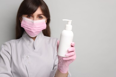 Cosmetologist with cosmetic product on grey background, selective focus