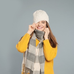 Photo of Happy young woman in warm clothes on grey background. Winter season