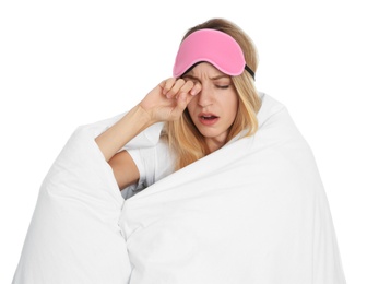 Tired woman in sleeping mask wrapped with soft blanket on white background