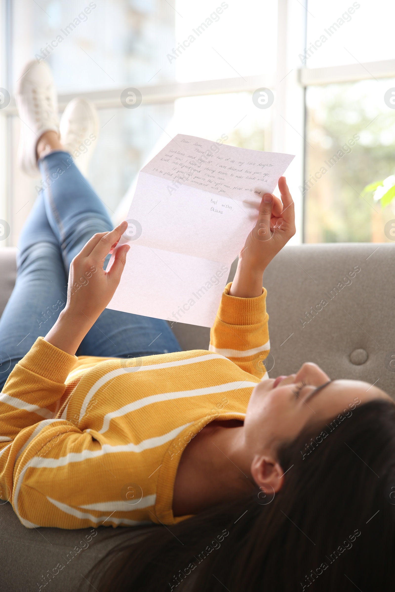 Photo of Woman reading letter on sofa at home, focus on hands