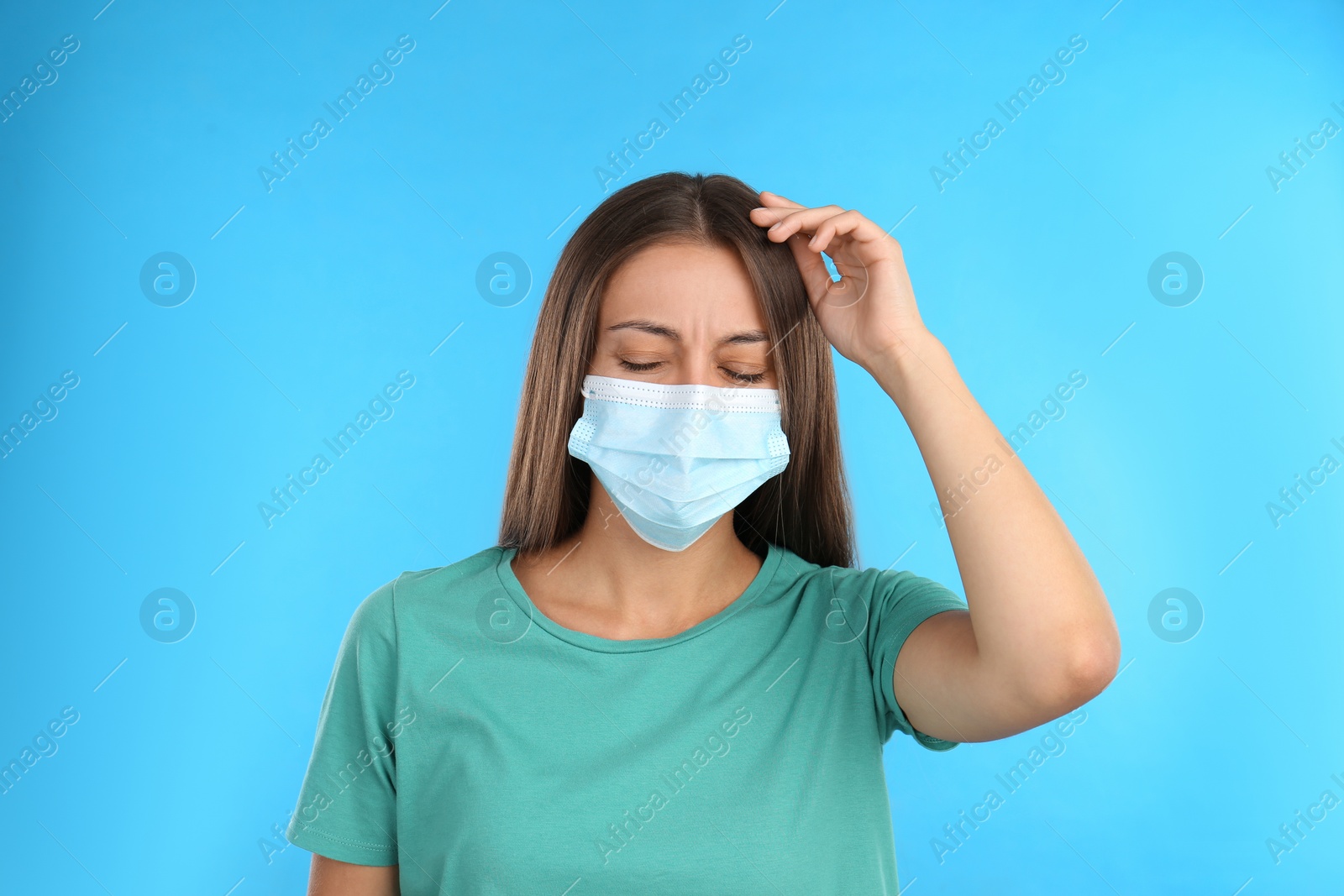 Photo of Stressed woman in protective mask on light blue background. Mental health problems during COVID-19 pandemic