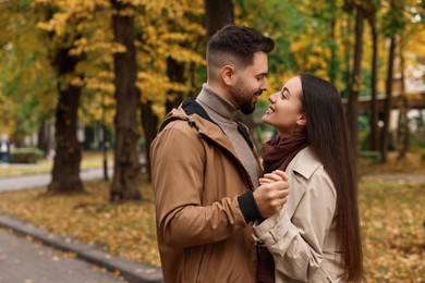 Romantic young couple spending time together in autumn park, space for text