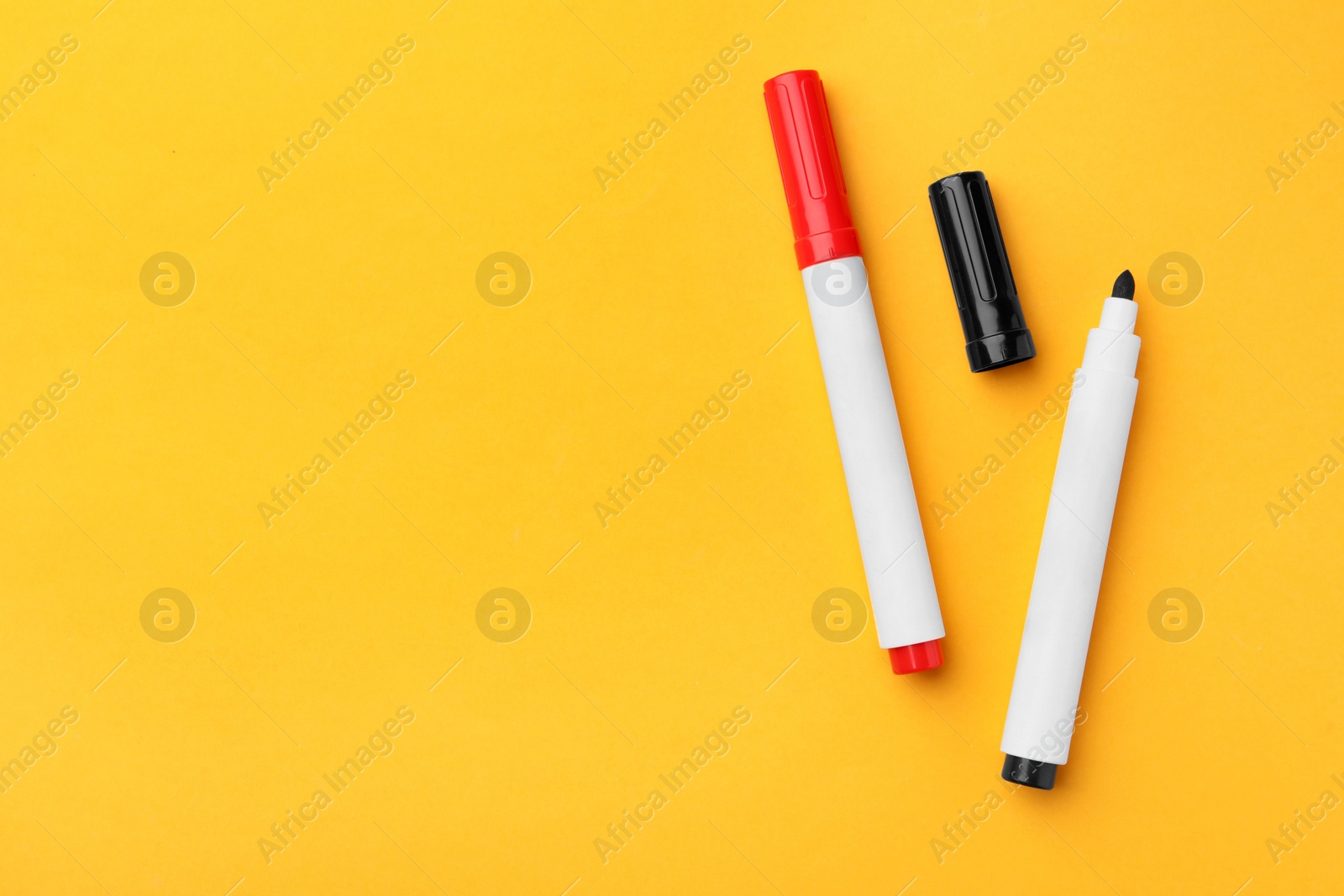 Photo of Bright color markers on orange background, flat lay. Space for text