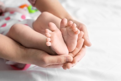 Photo of Mother holding feet of her cute little baby in hands, closeup