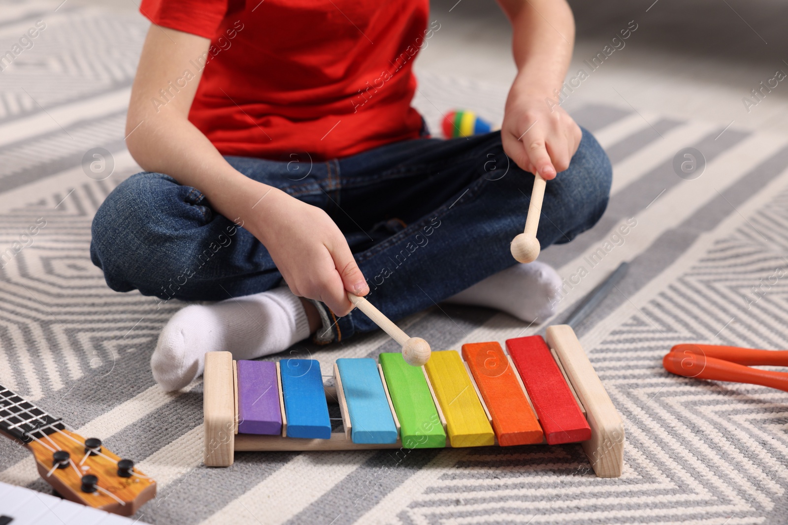 Photo of Little boy playing toy xylophone at home, closeup