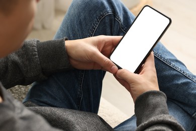 Photo of Man using smartphone with blank screen indoors, closeup. Mockup for design