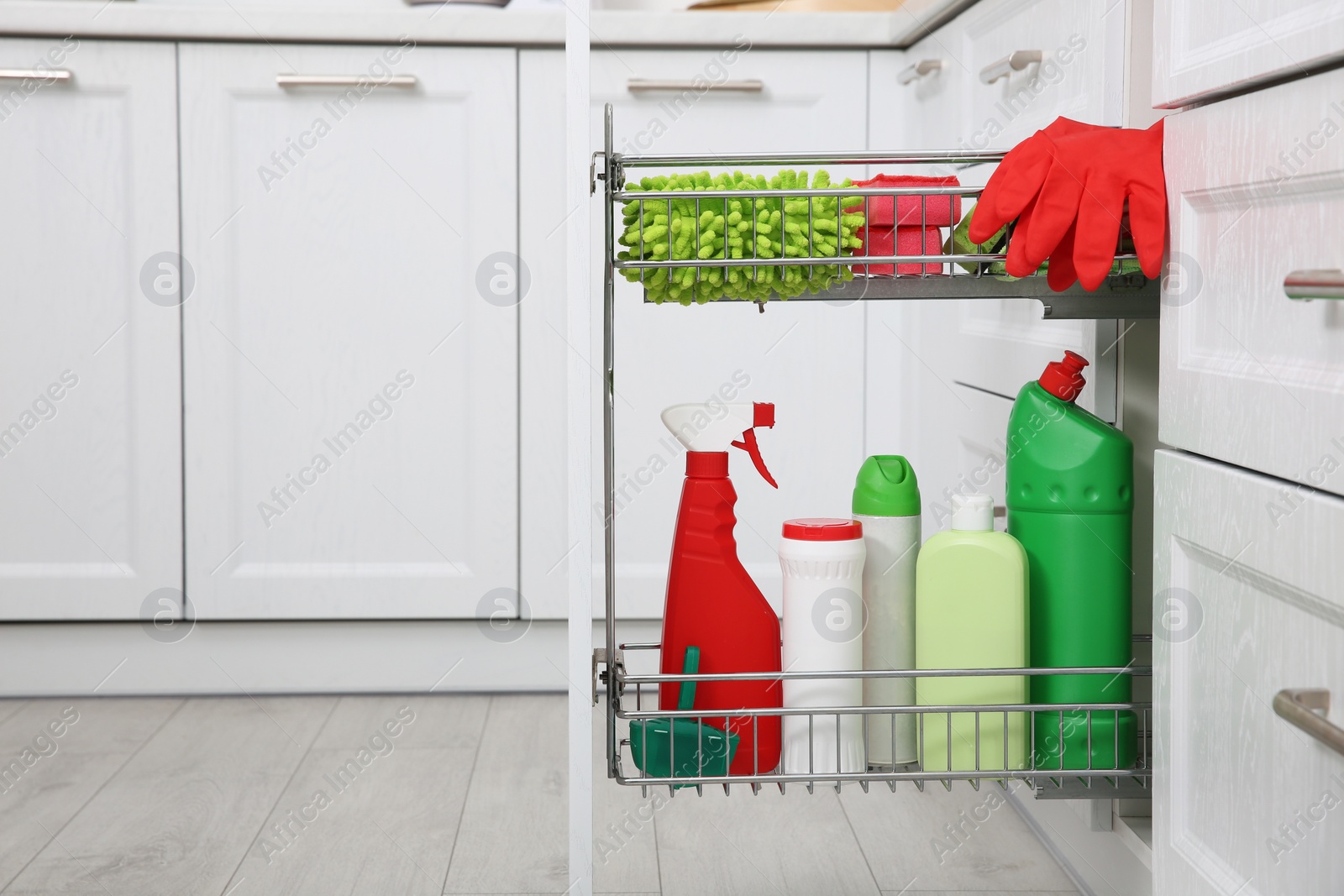 Photo of Open drawer with different cleaning supplies in kitchen. Space for text