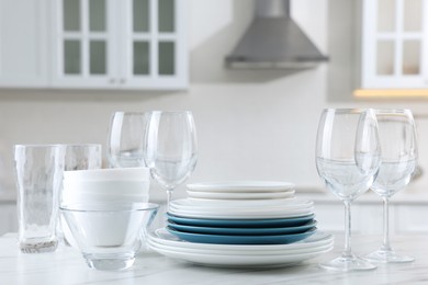 Photo of Different clean dishware and glasses on white marble table in kitchen