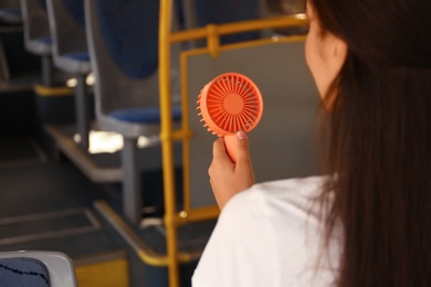 Photo of Woman with portable fan in bus, closeup. Summer heat