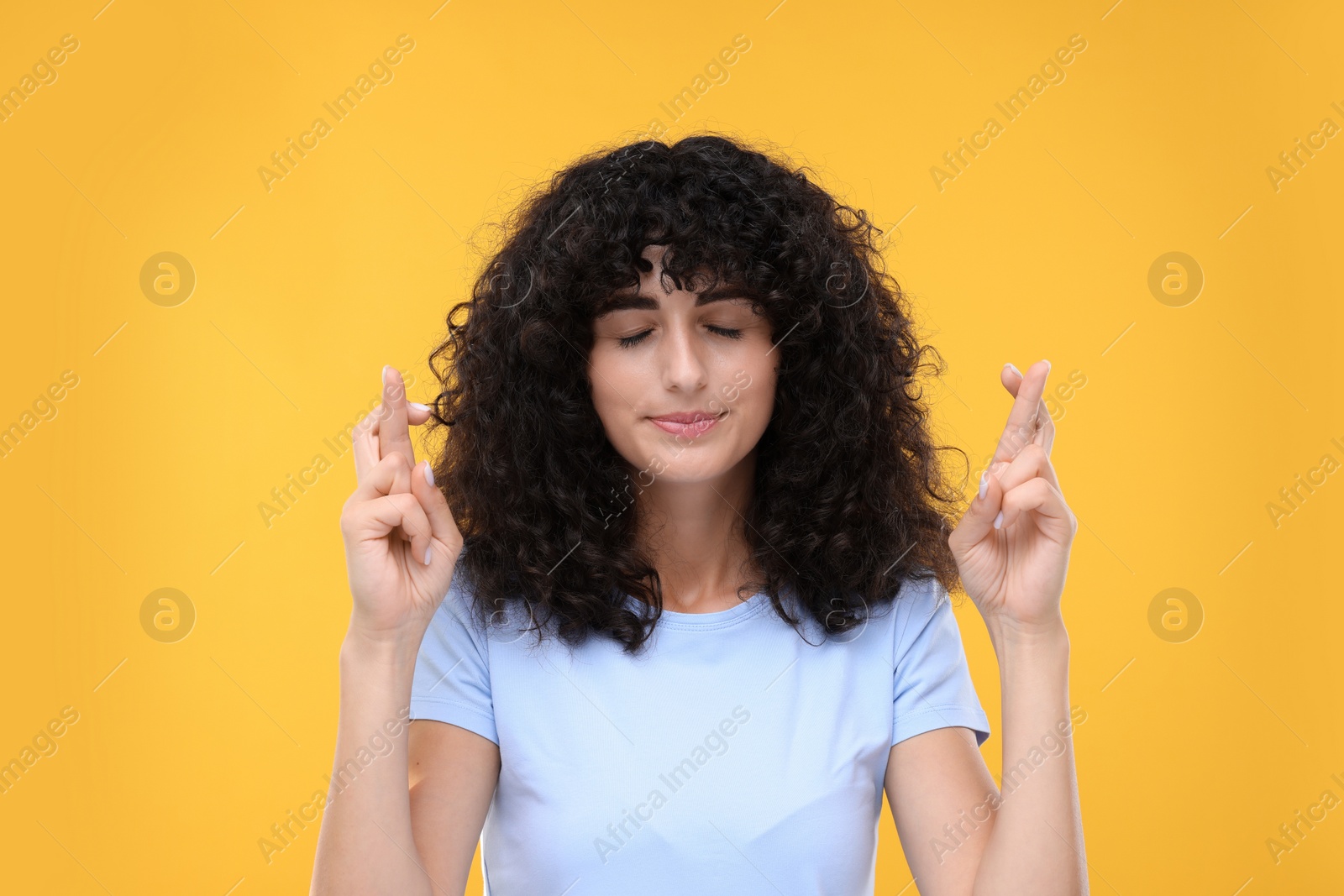 Photo of Woman crossing her fingers on yellow background