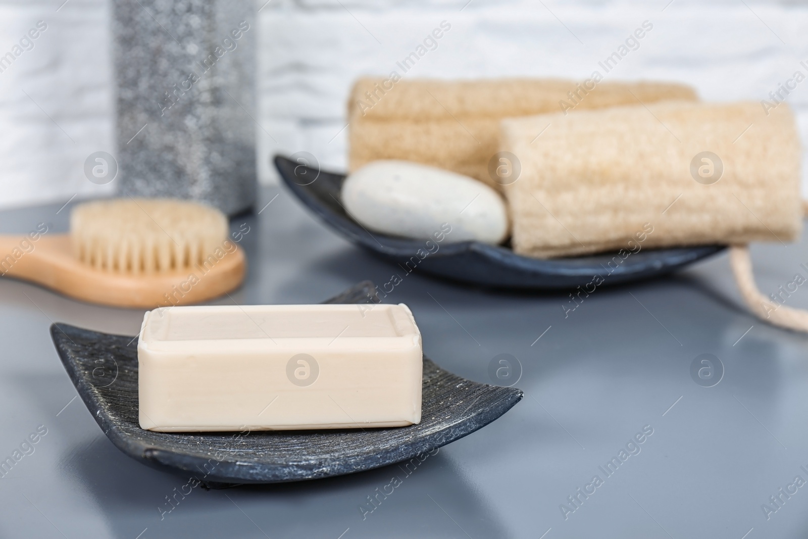 Photo of Dish with soap bar on grey table. Space for text