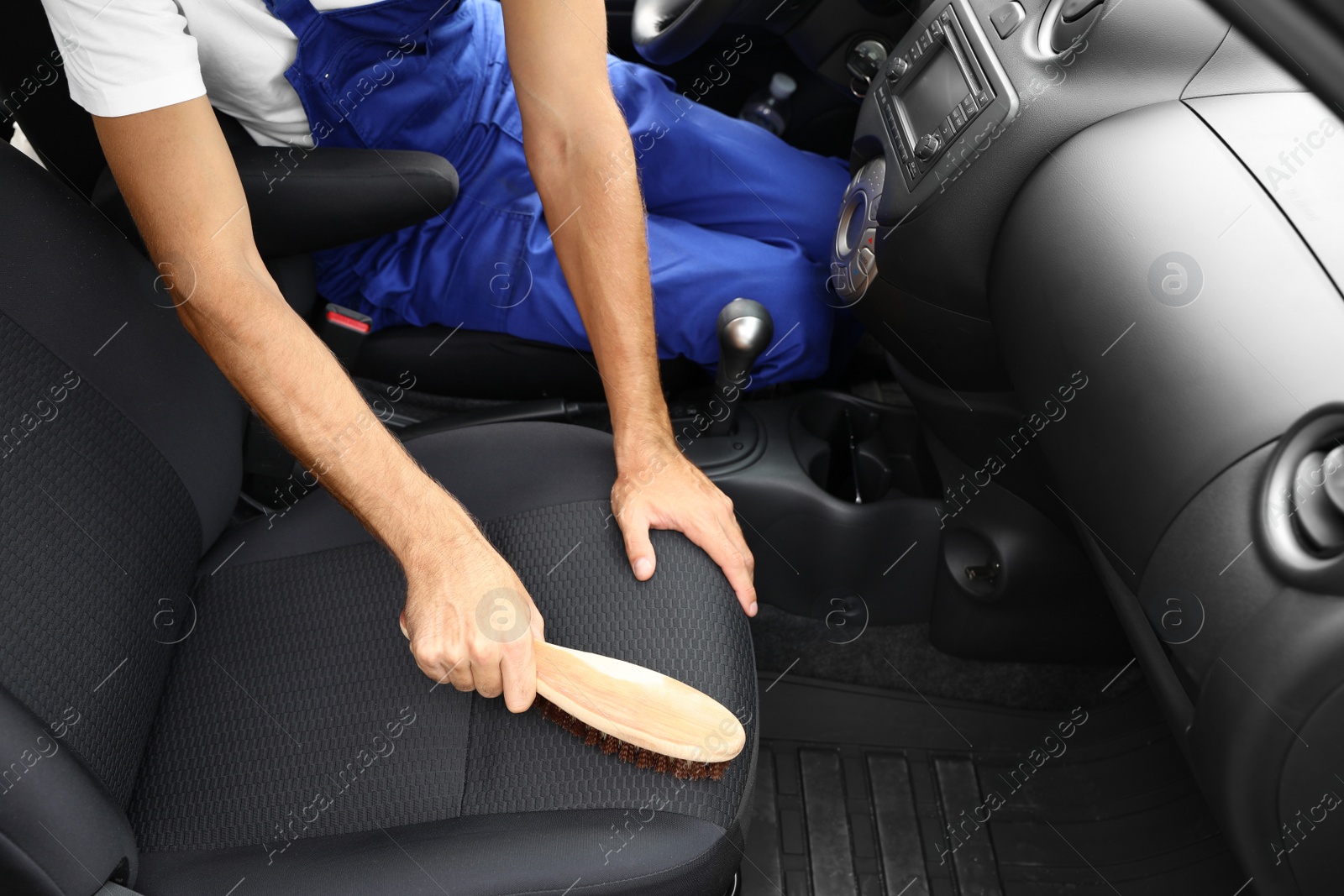 Photo of Man cleaning automobile salon with brush, closeup. Car wash service