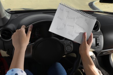 Photo of Woman with to do list in driver's seat of car, closeup. Stress overload concept