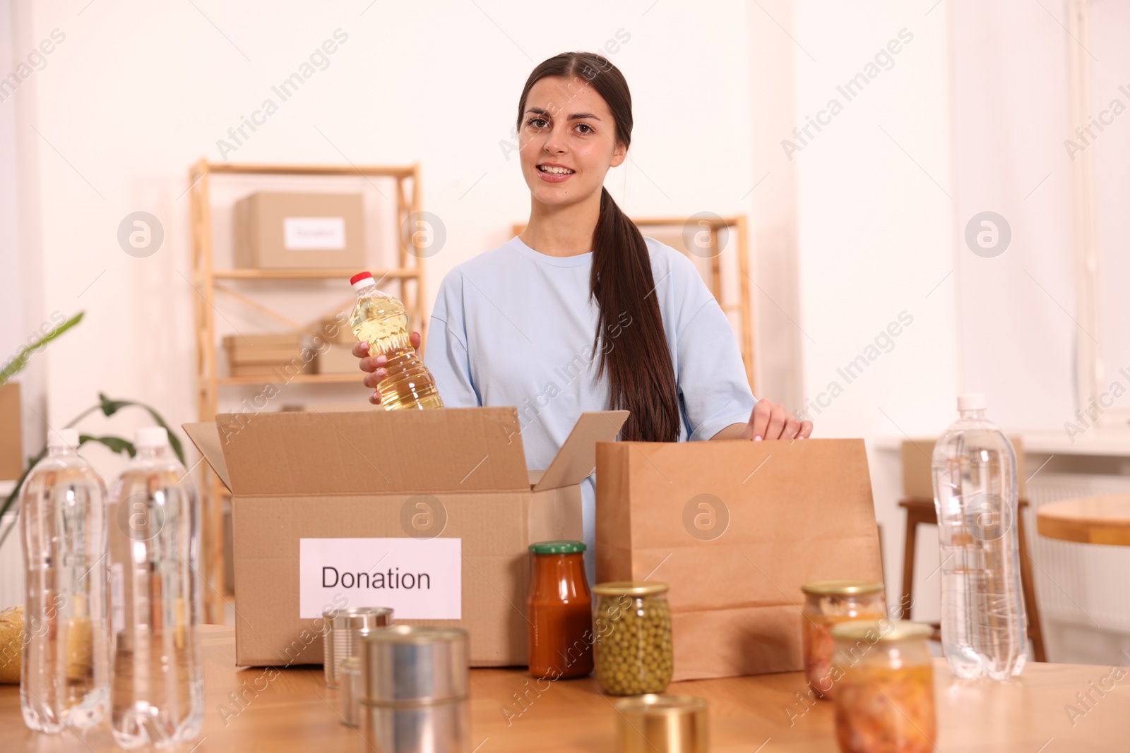 Photo of Volunteer packing food products at table in warehouse