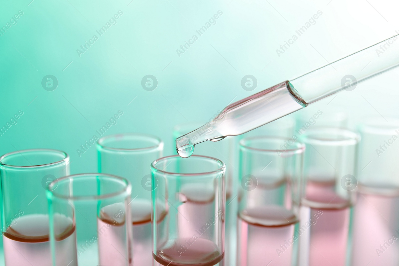 Photo of Dropping sample into test tube with liquid on color background, closeup