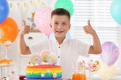 Happy boy at table with treats in room decorated for birthday party