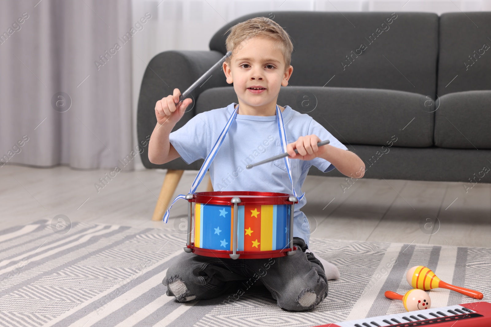 Photo of Little boy playing toy drum at home