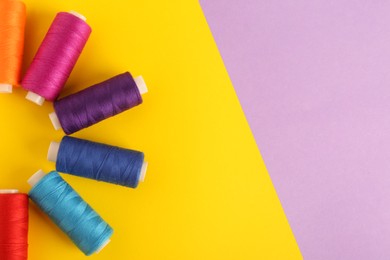 Photo of Different sewing threads on color background, flat lay. Space for text