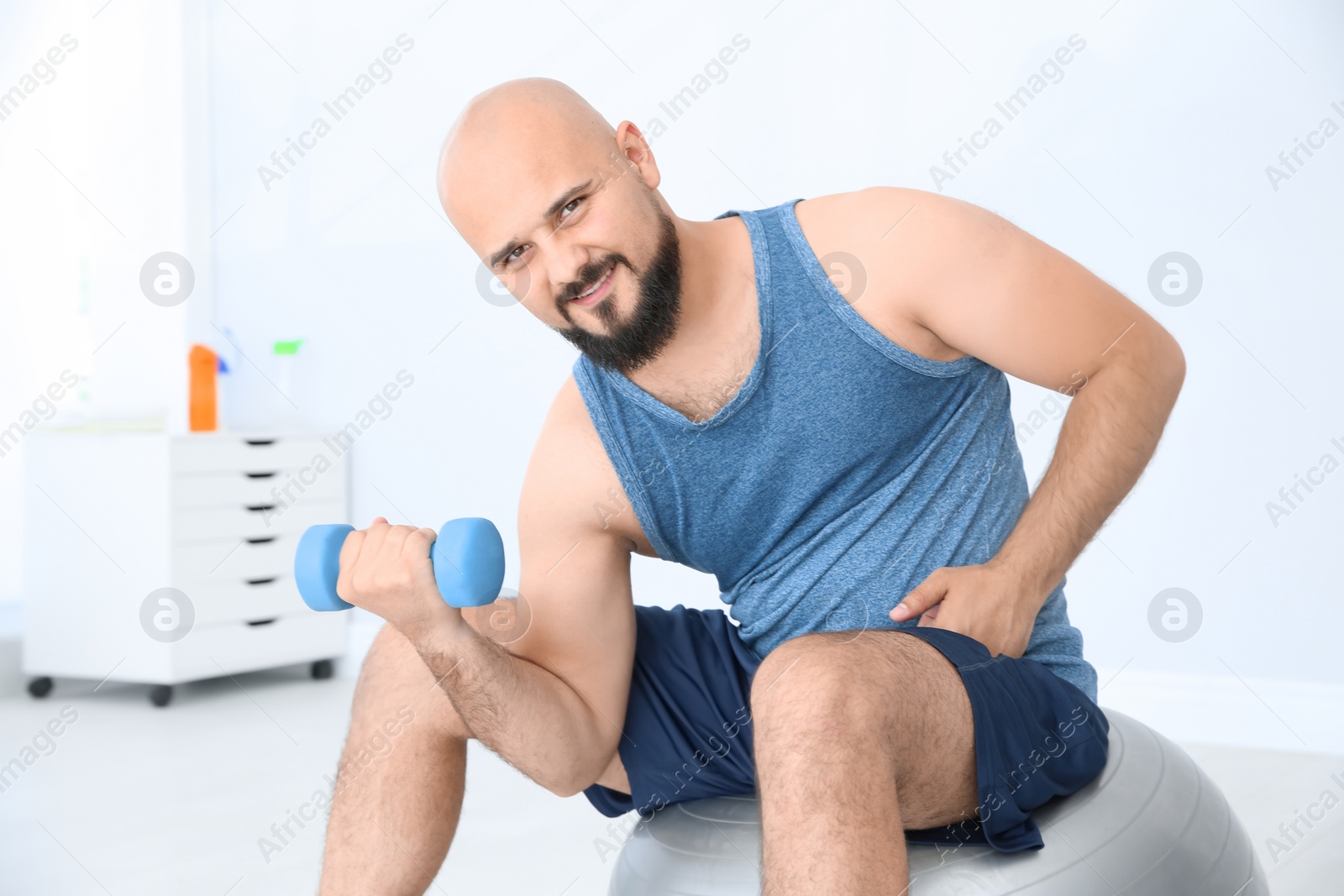 Photo of Overweight man doing exercise with dumbbell in gym