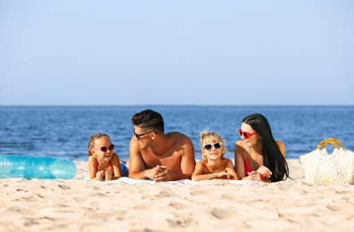Photo of Happy family on sandy beach near sea. Summer holidays