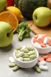 Photo of Dietary supplements. Different pills in bowls and food products on grey table