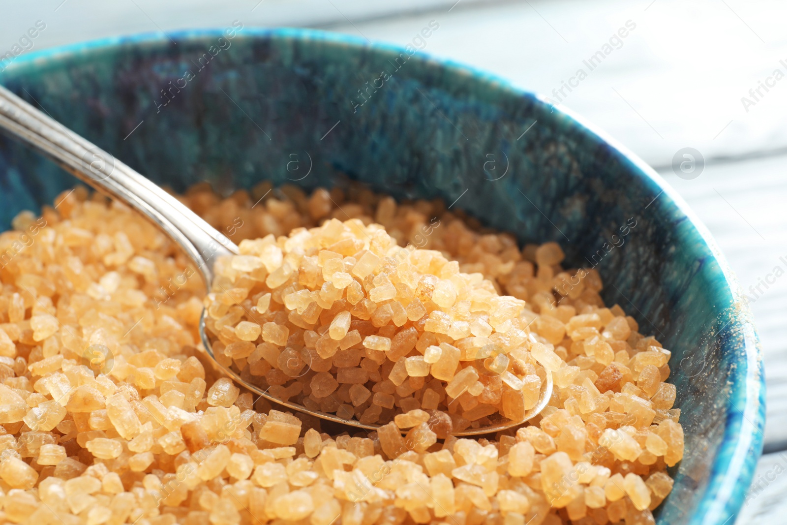 Photo of Spoon with brown sugar in bowl, closeup