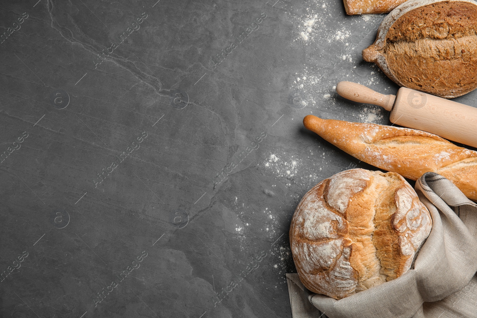 Photo of Different kinds of fresh bread on grey table, flat lay. Space for text