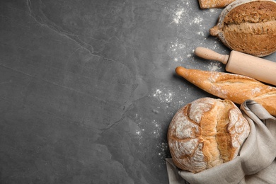 Different kinds of fresh bread on grey table, flat lay. Space for text