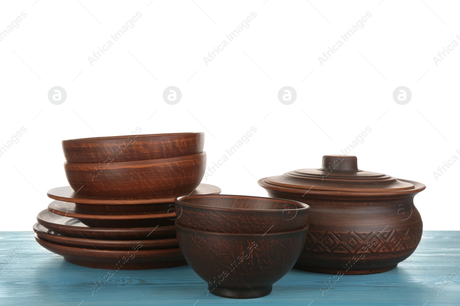 Photo of Different clay dishware on light blue wooden table against white background