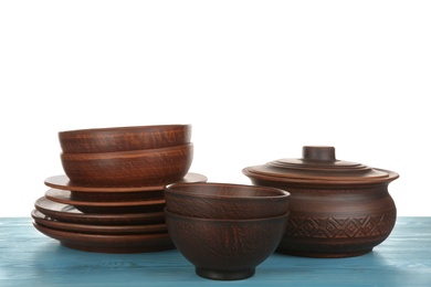 Different clay dishware on light blue wooden table against white background