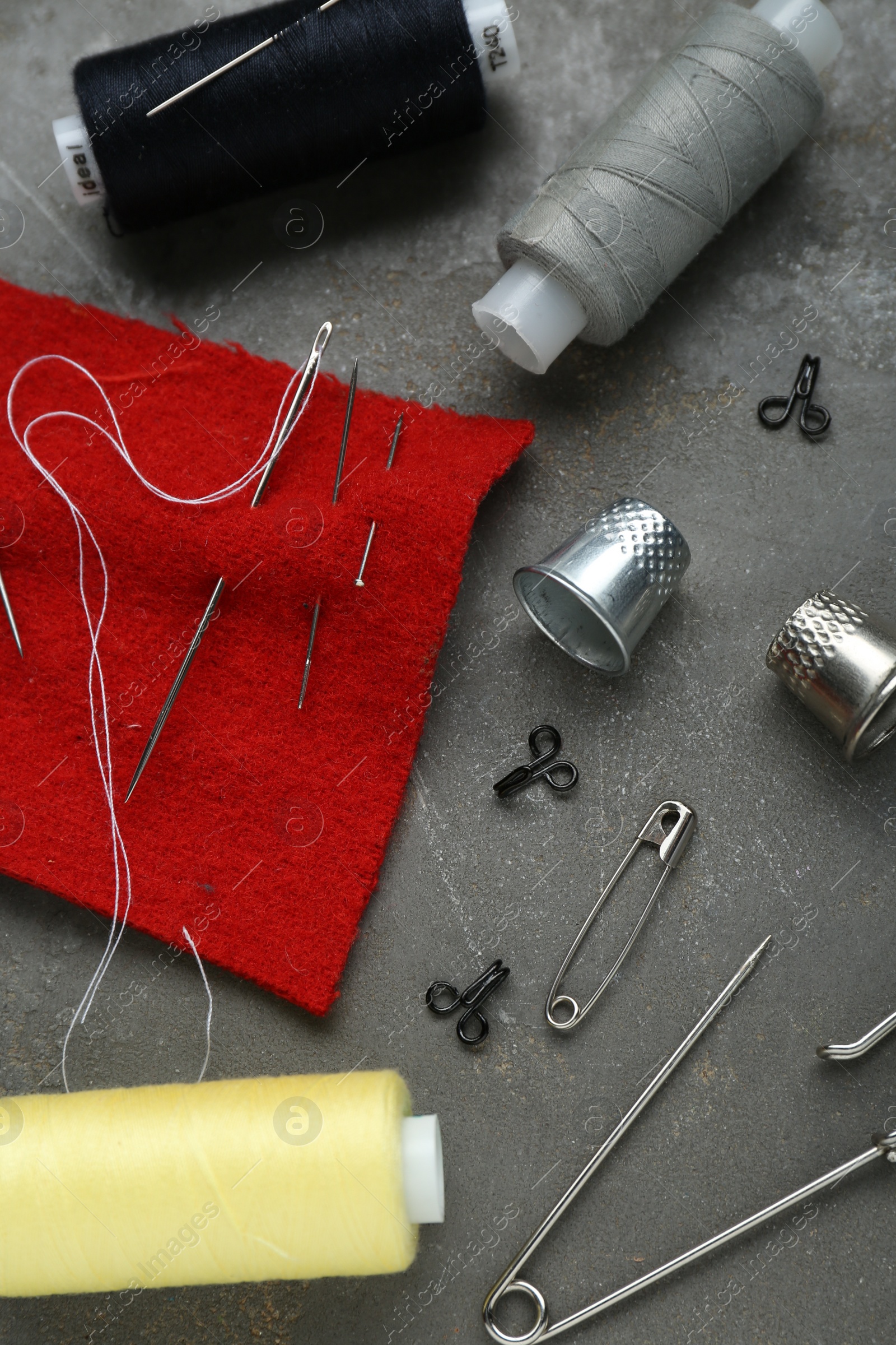 Photo of Flat lay composition with thimbles and different sewing tools on grey table