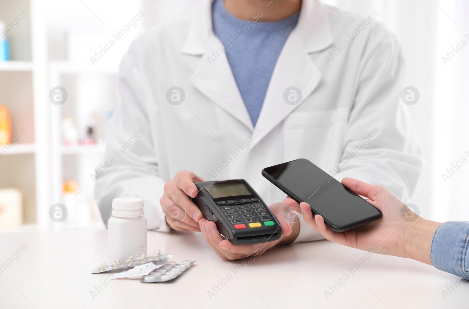 Photo of Woman using terminal for contactless payment with smartphone in pharmacy, closeup