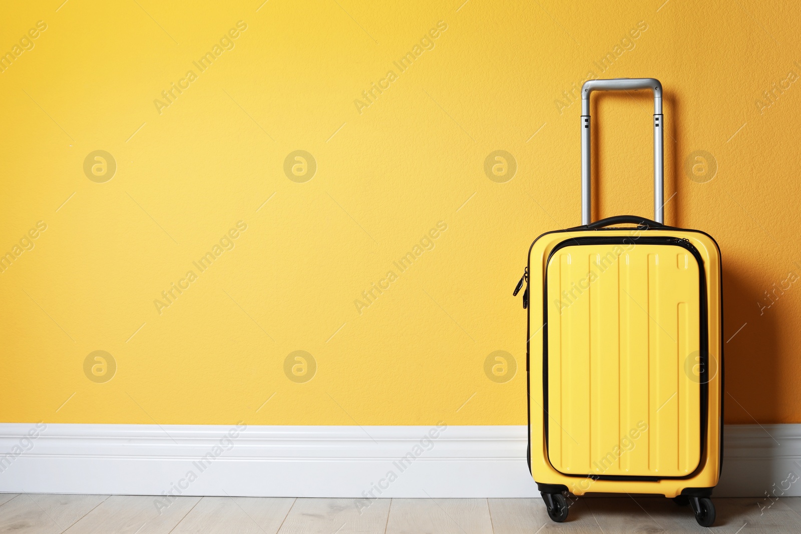 Photo of Bright yellow suitcase near color wall