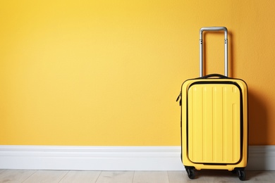 Photo of Bright yellow suitcase near color wall