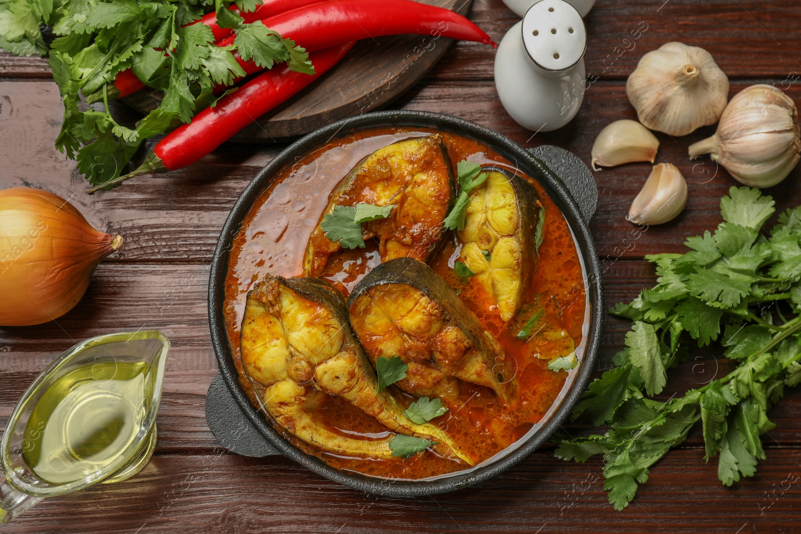 Photo of Tasty fish curry and ingredients on wooden table, flat lay. Indian cuisine